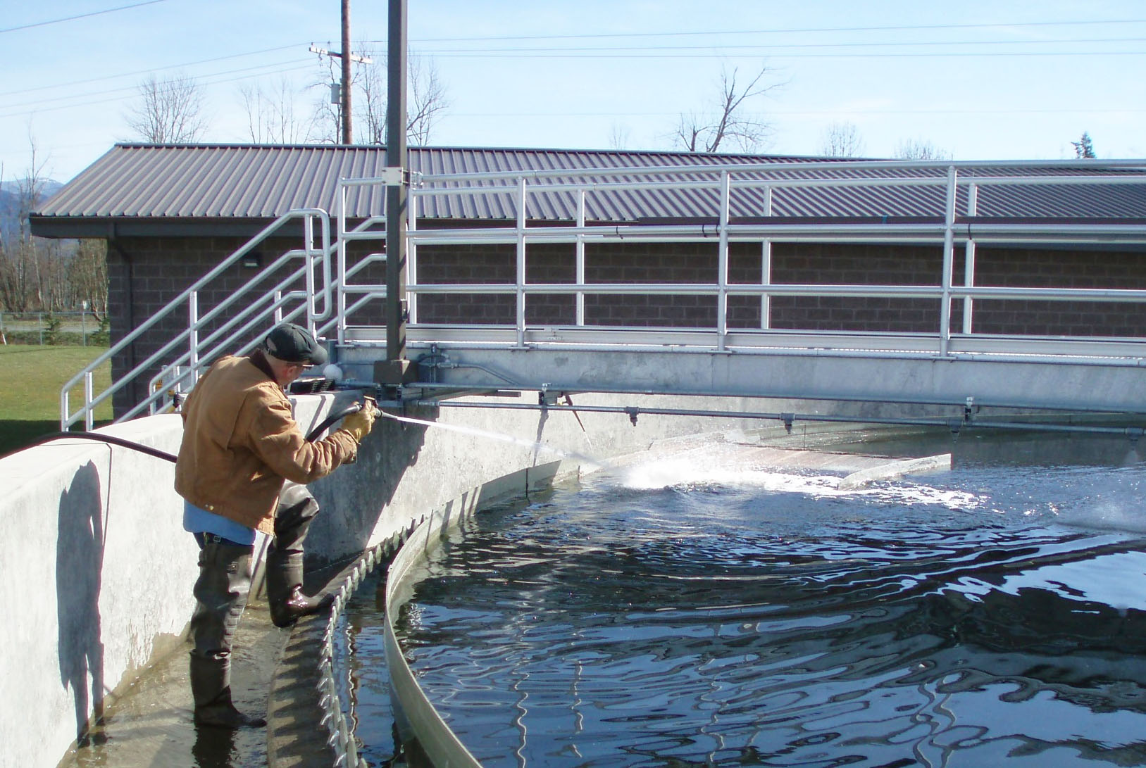 A wastewater operator spraying water into a large water tank