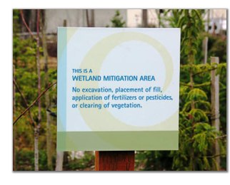 A sign identifying a wetland mitigation area that reads, "This is a wetland mitigation area. No excavation, placement of fill, application of fertilizers or pesticides, or clearing of vegetation."